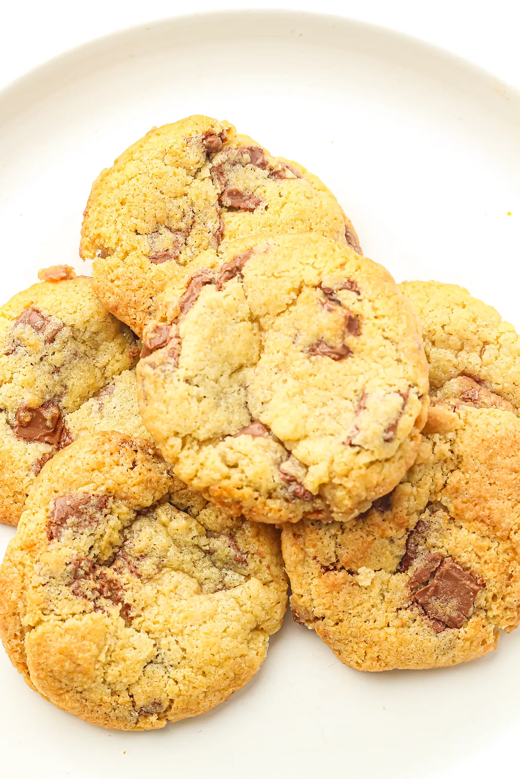 Chocolate chunk cookies baked from freezer cookie dough, piled on a white plate