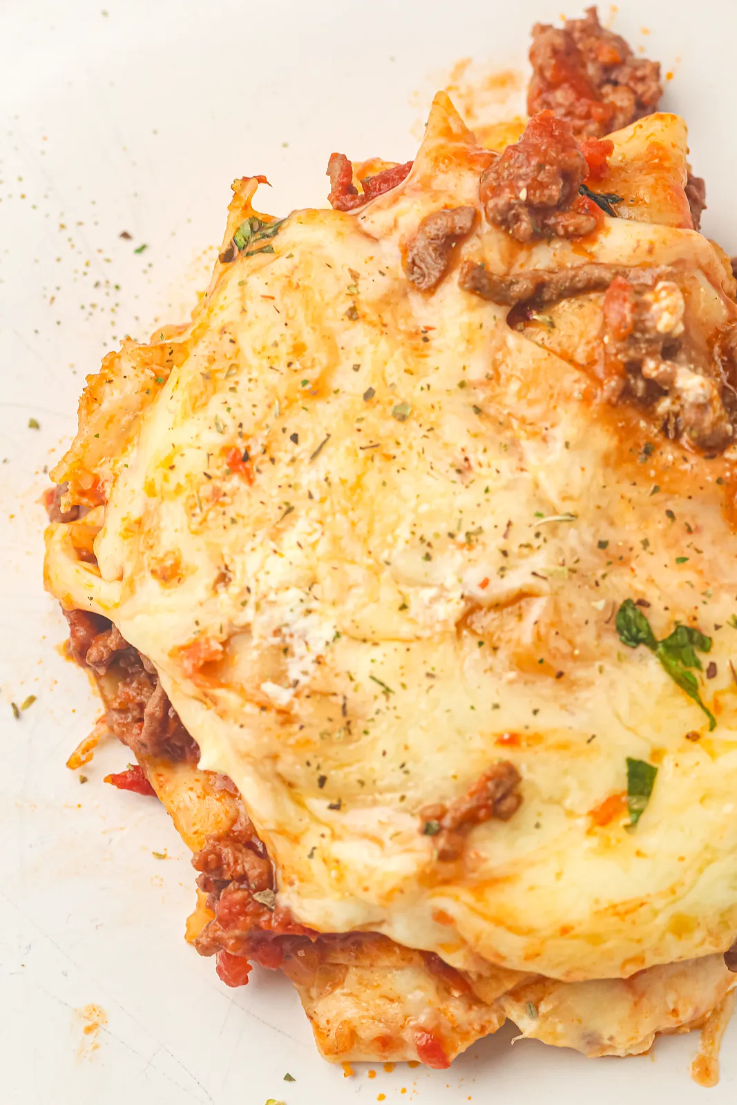 Close up of a golden mozzarella crust over beef ragu and soft pasta sheets