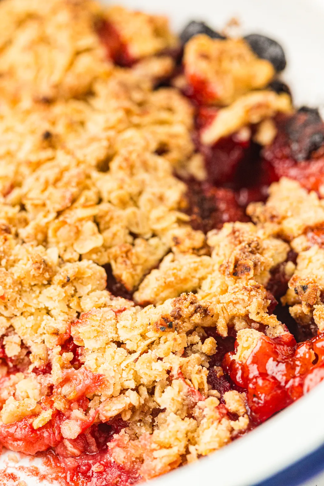 Close up of the golden, craggy oat topping with glossy red fruit peeking through