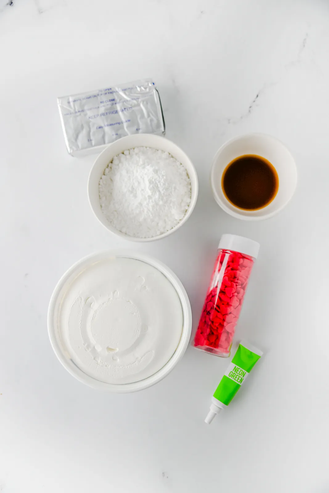 Ingredients for grinch dip: cream cheese, powdered sugar, vanilla, whipped topping, green gel colour and heart sprinkles