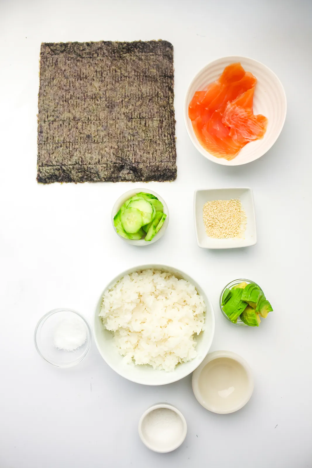 Ingredients for ice cube tray sushi: nori sheet, smoked salmon, cooked rice, cucumber, avocado, sesame seeds, vinegar, sugar and salt