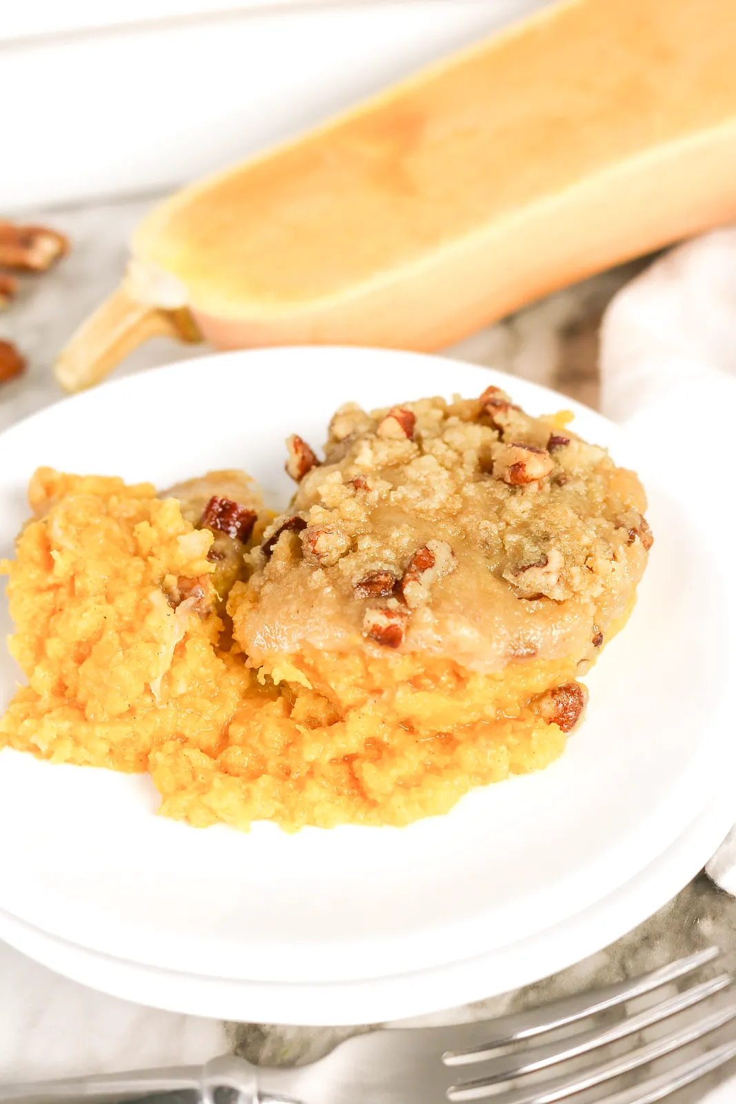 A scoop of golden mash with a brown sugar pecan crumble on a white plate