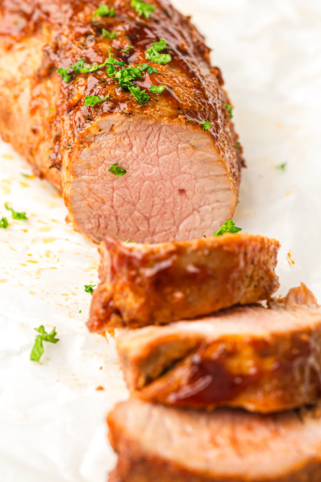 Ninja Woodfire pork tenderloin, sliced to show the juicy pink centre, with BBQ glaze and parsley