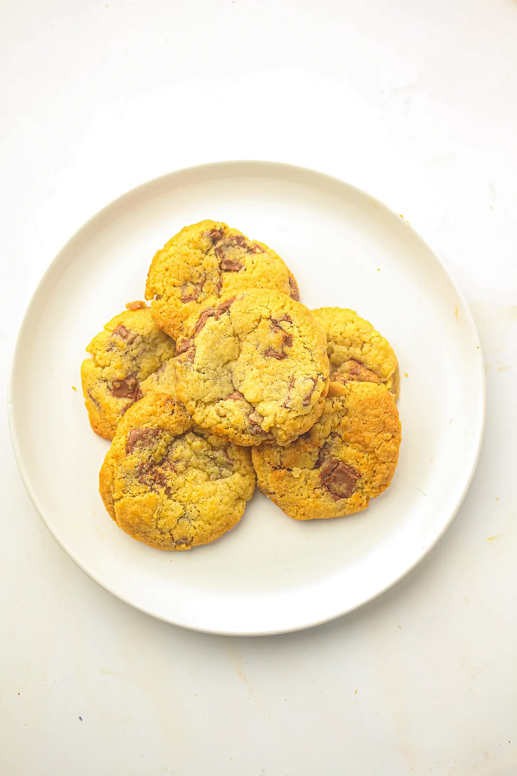 Overhead view of golden chocolate chunk bakes on a white plate