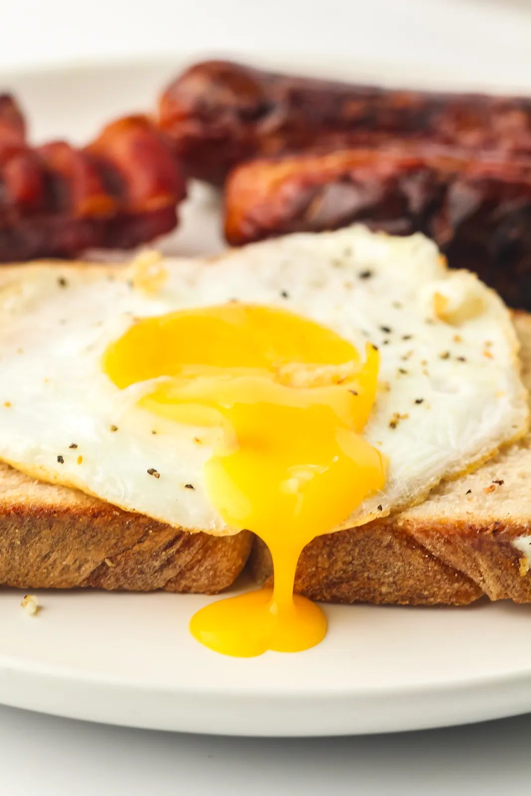 Golden runny yolk dripping off a fried egg on toast