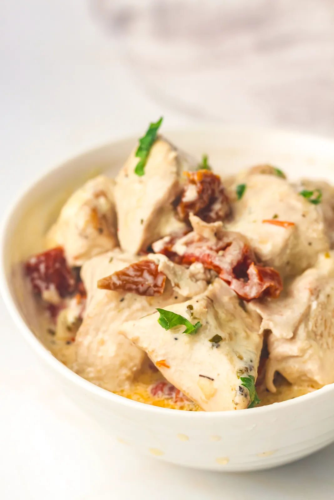 Close up of seared pieces and sun-dried tomatoes coated in a pale cream sauce