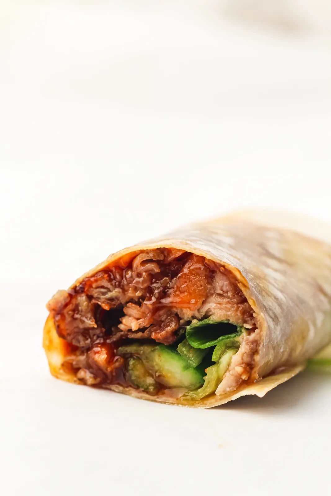 Close up of one cut roll filled with shredded meat and cucumber