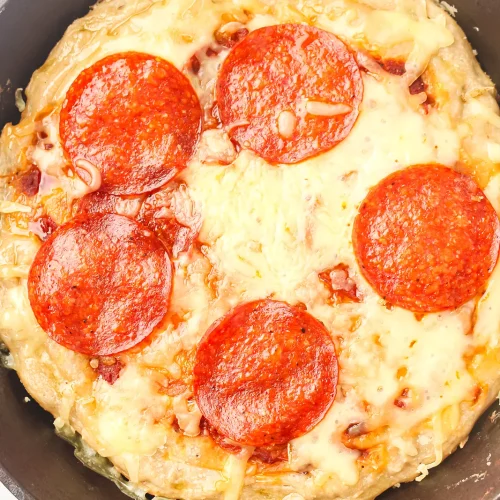 Skillet pizza with pepperoni and melted mozzarella in a cast iron pan