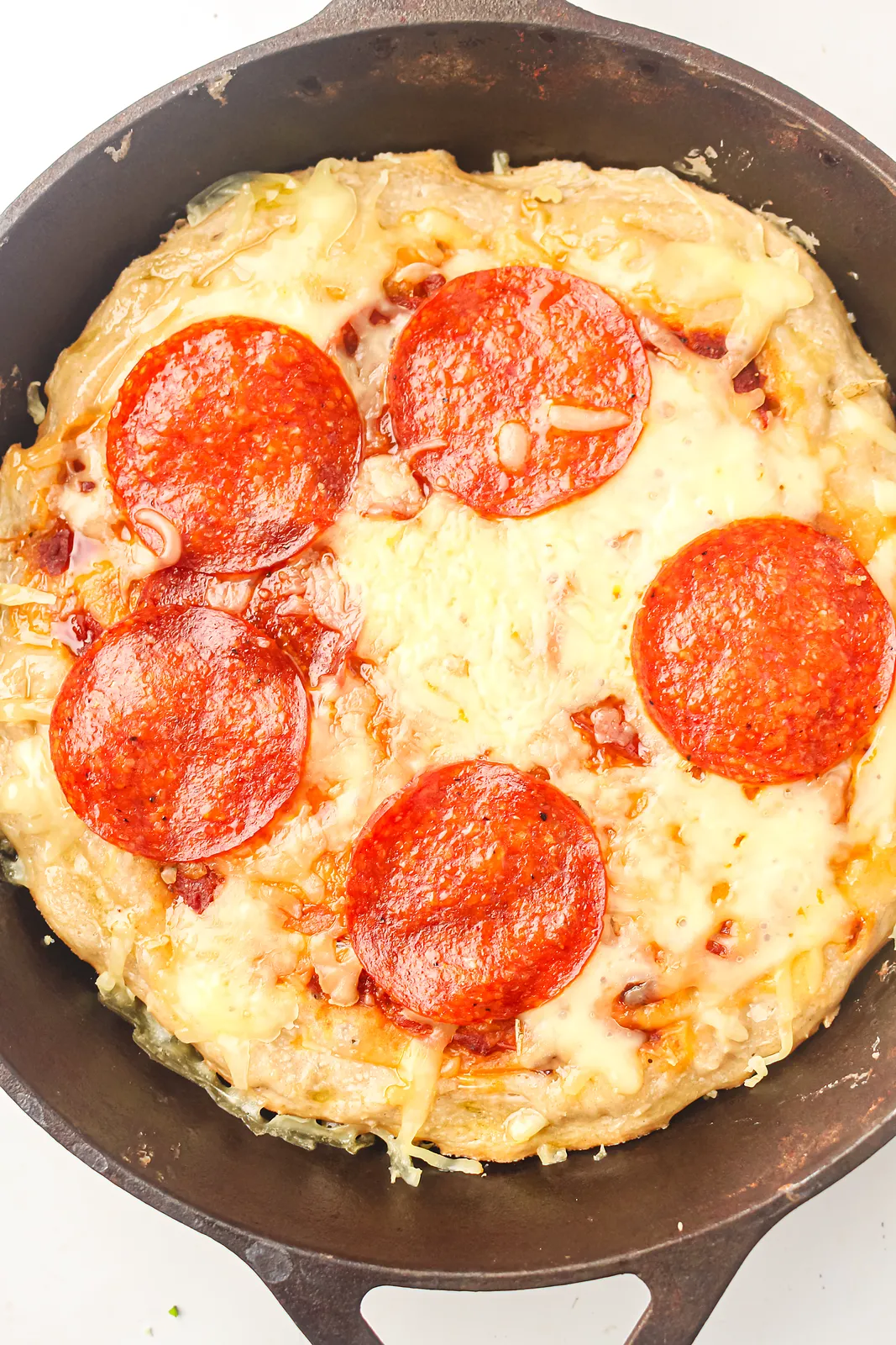 Skillet pizza with pepperoni and melted mozzarella in a cast iron pan