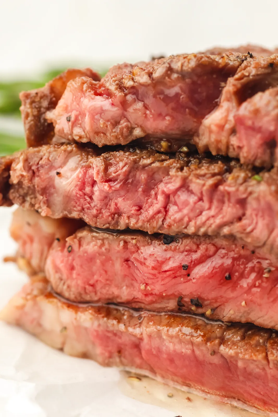 A stack of sliced medium rare steak showing a pink centre and brown crust