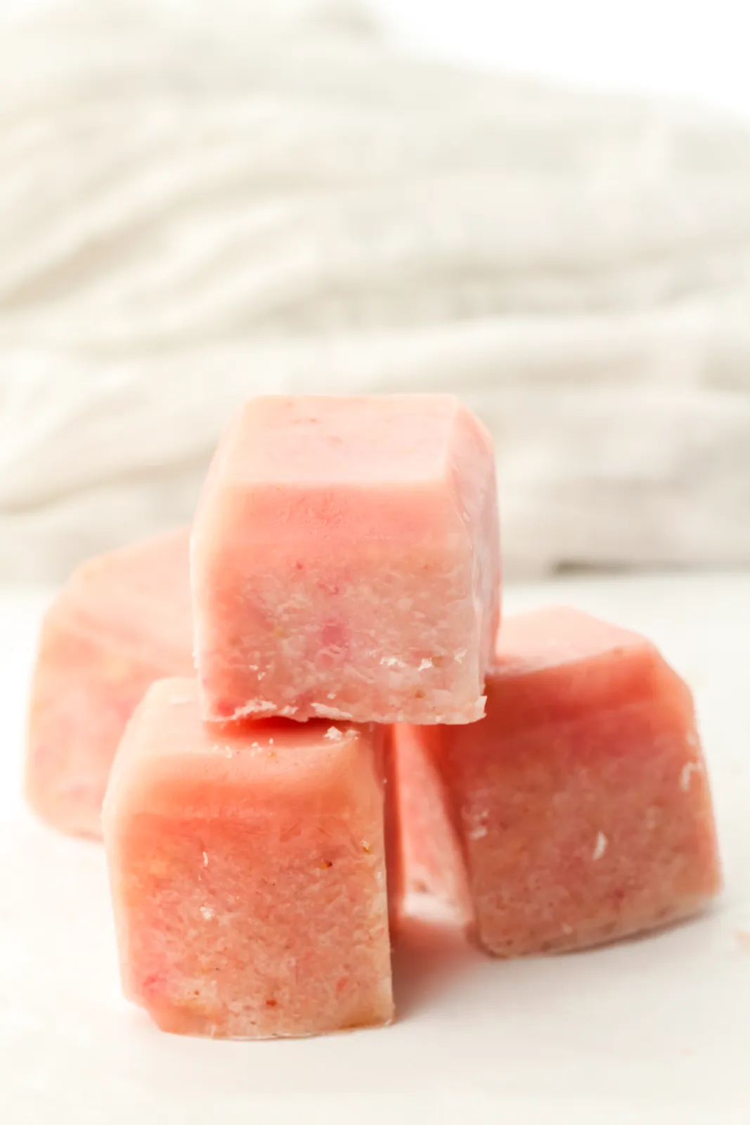 Strawberry banana smoothie cubes stacked on a white surface
