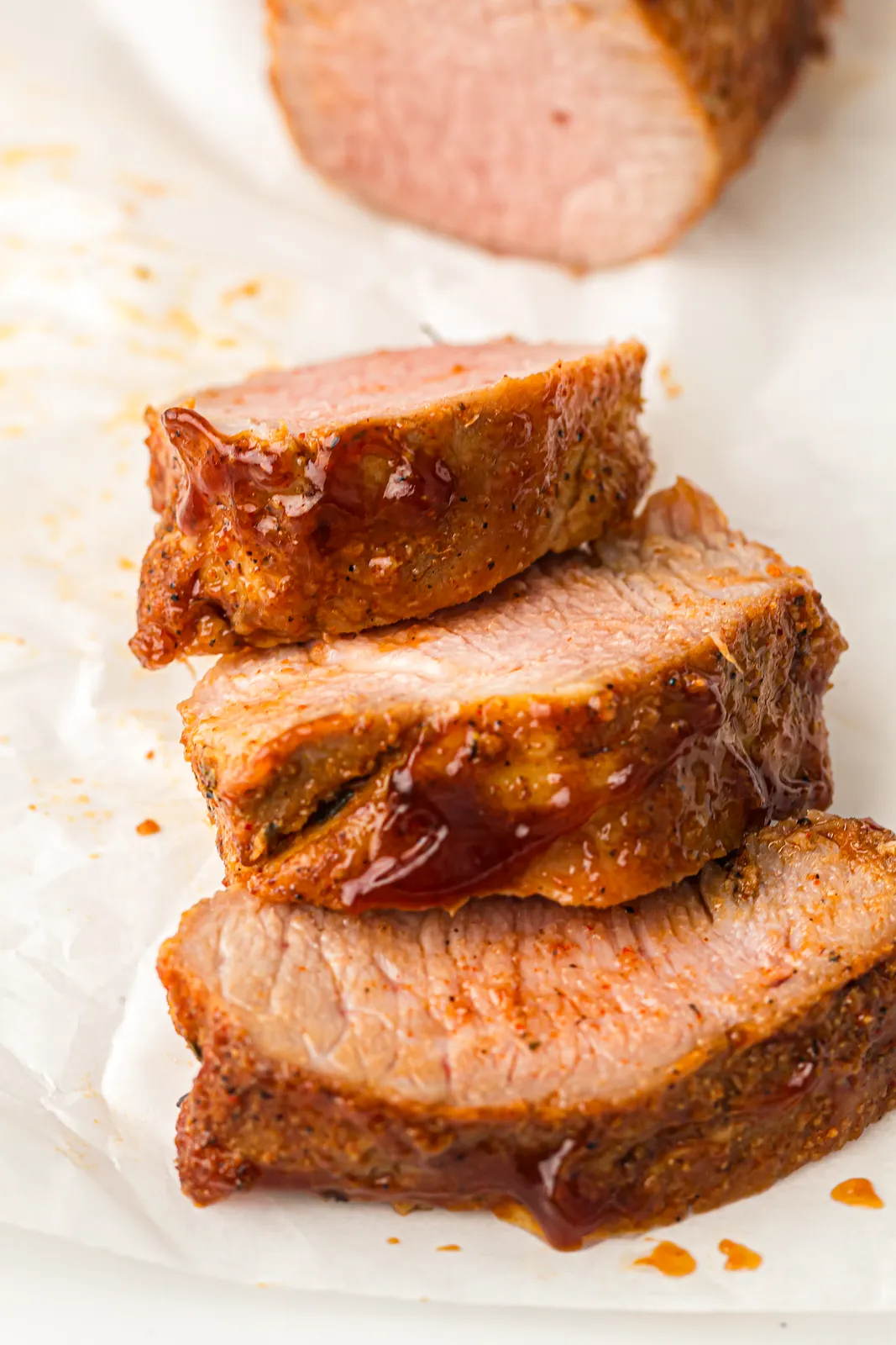 Three thick, juicy slices stacked on parchment with drips of sticky sauce