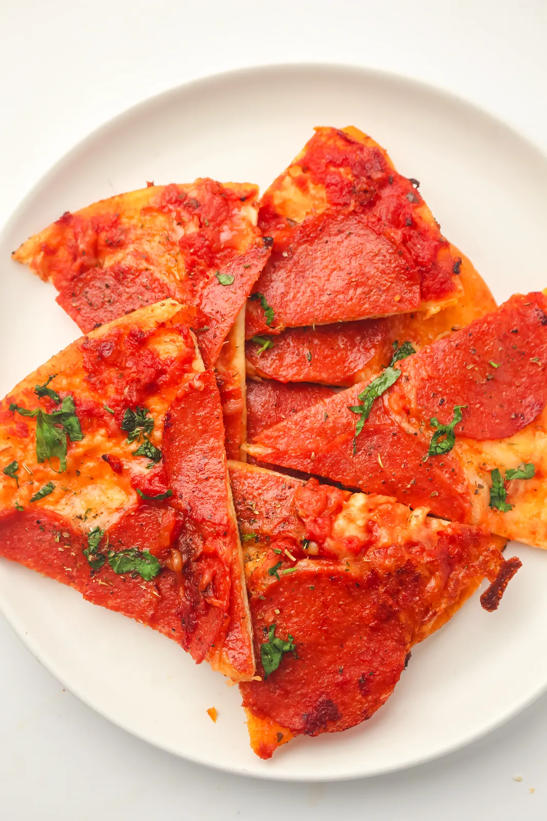 Stacked crispy pepperoni wedges on a white plate