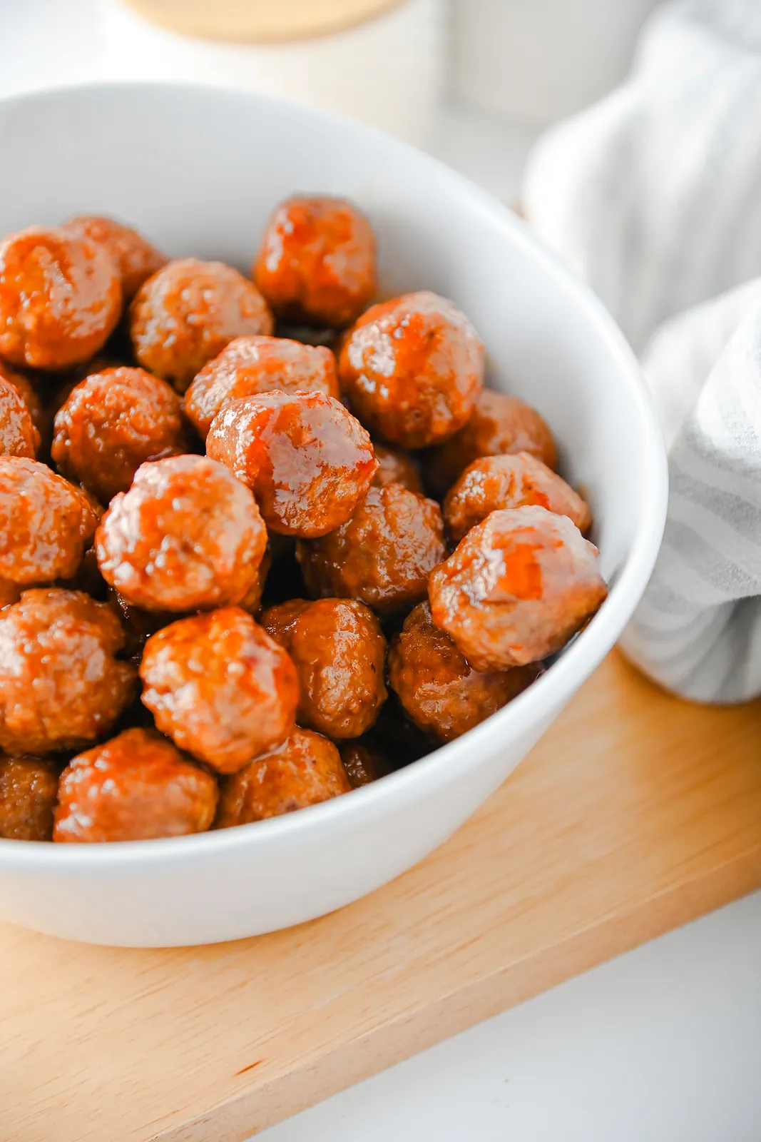 Close up of sticky chili glazed meatballs piled in a white bowl