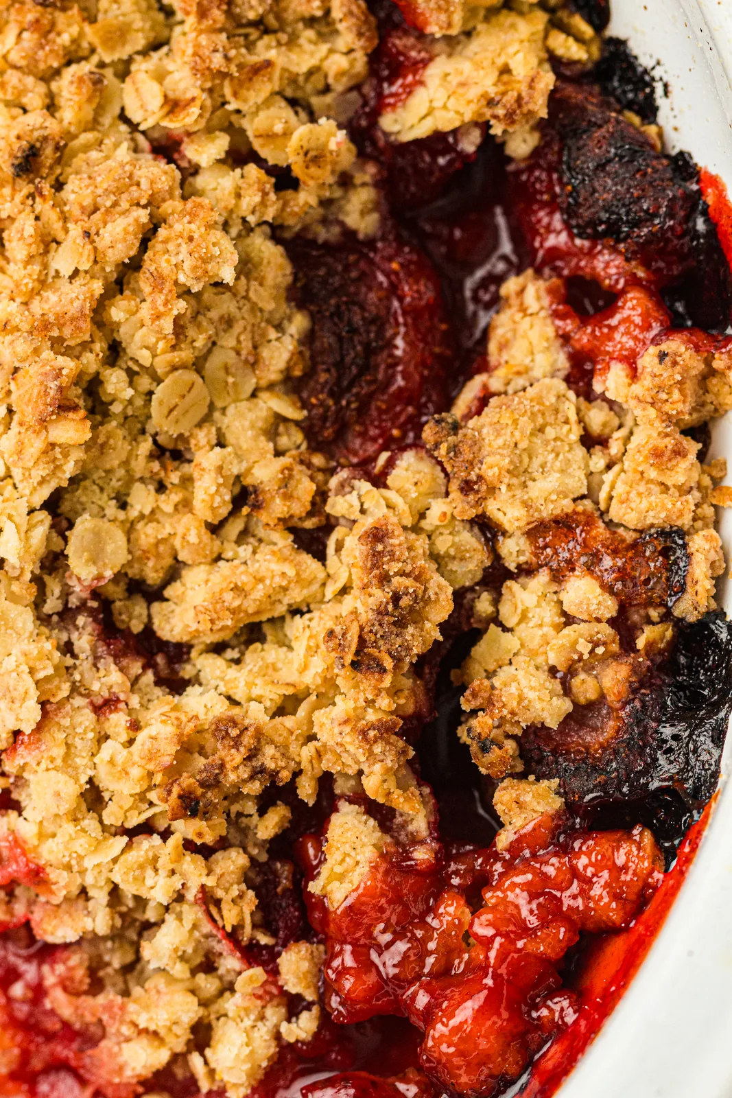 Strawberry crumble baked in a white dish with a golden oat topping and bubbling red fruit