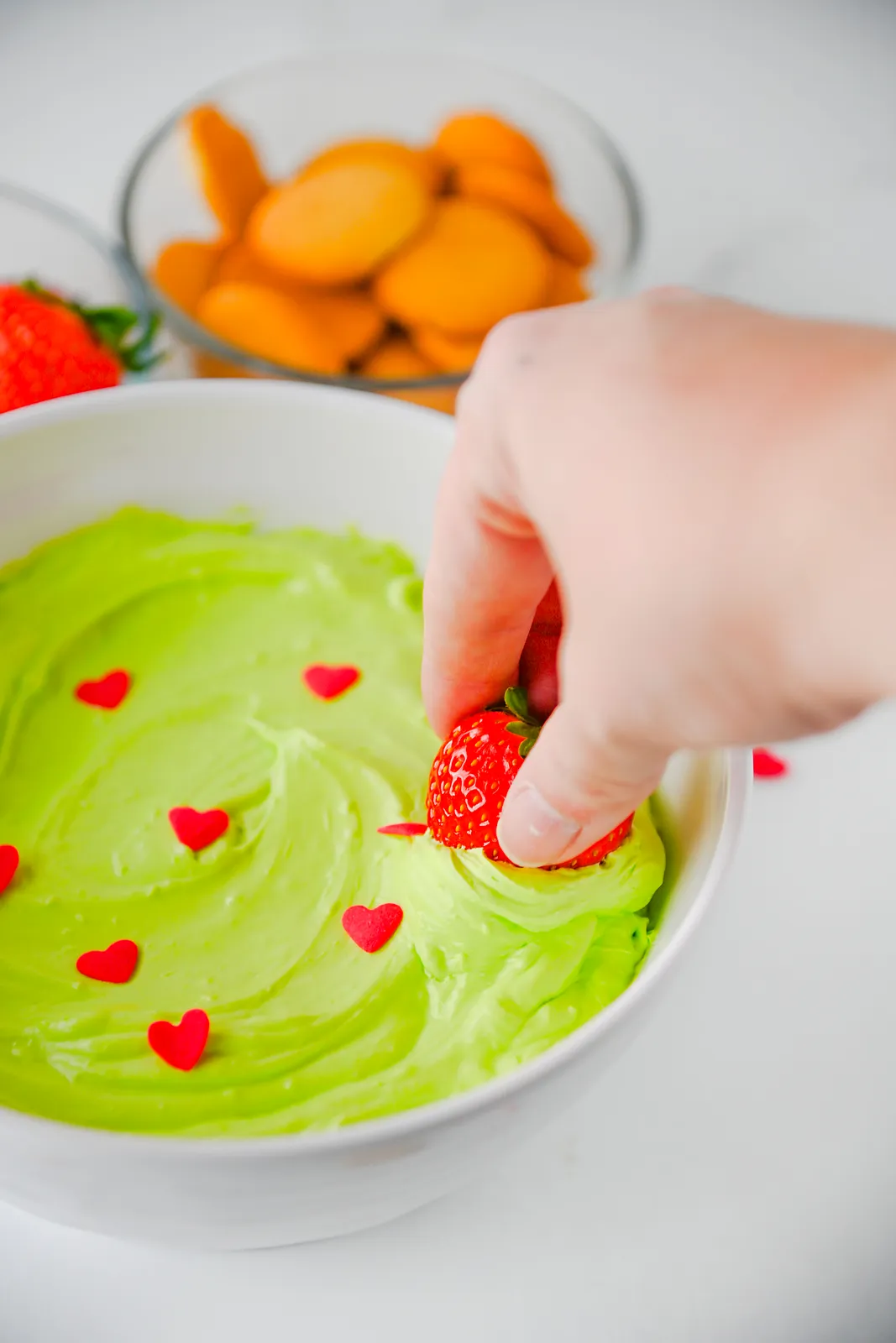 A strawberry pushed into green fluff with red heart sprinkles