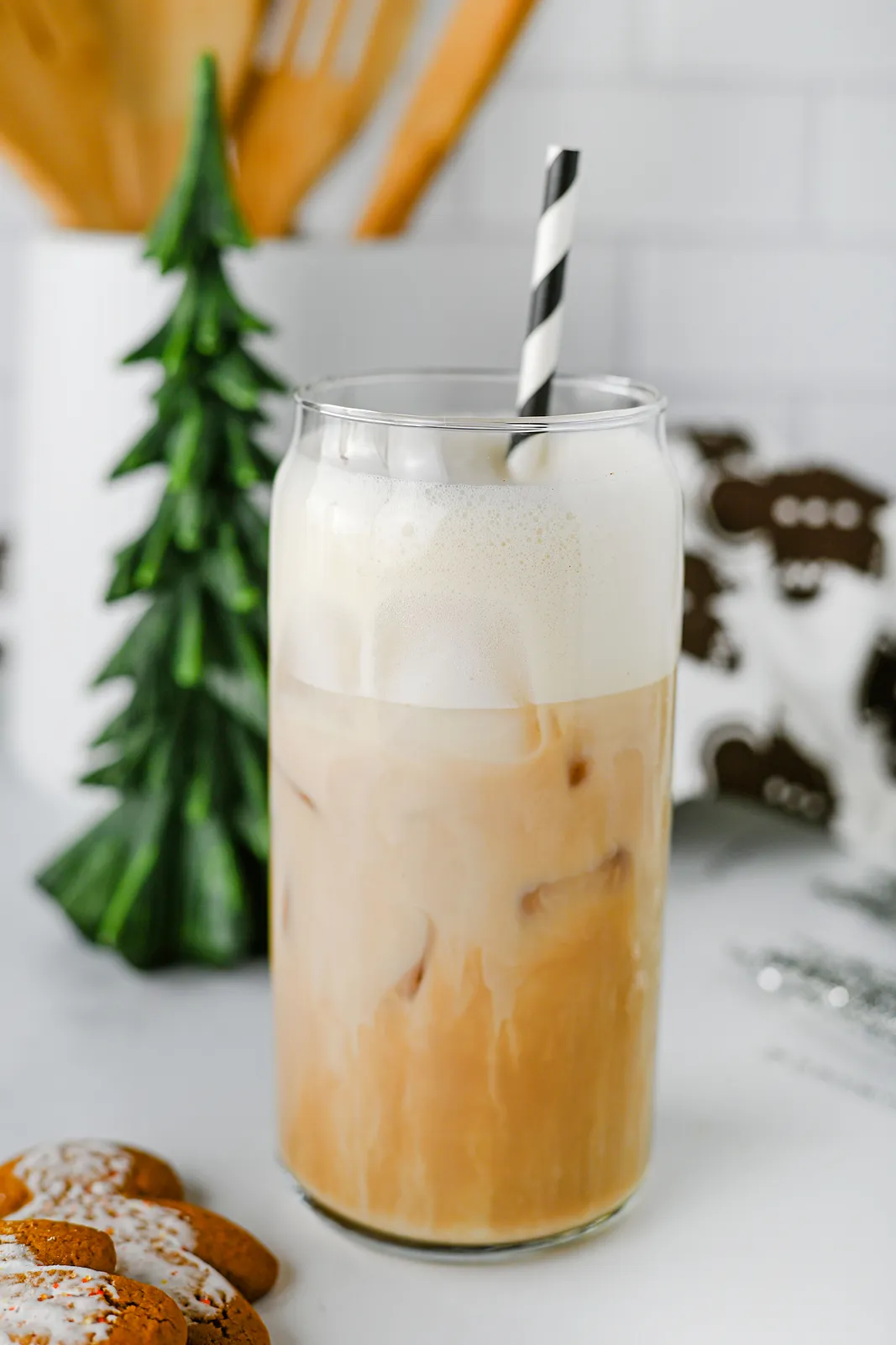 Close up of a tall glass with a thick cap of oat milk foam over a spiced, milky drink