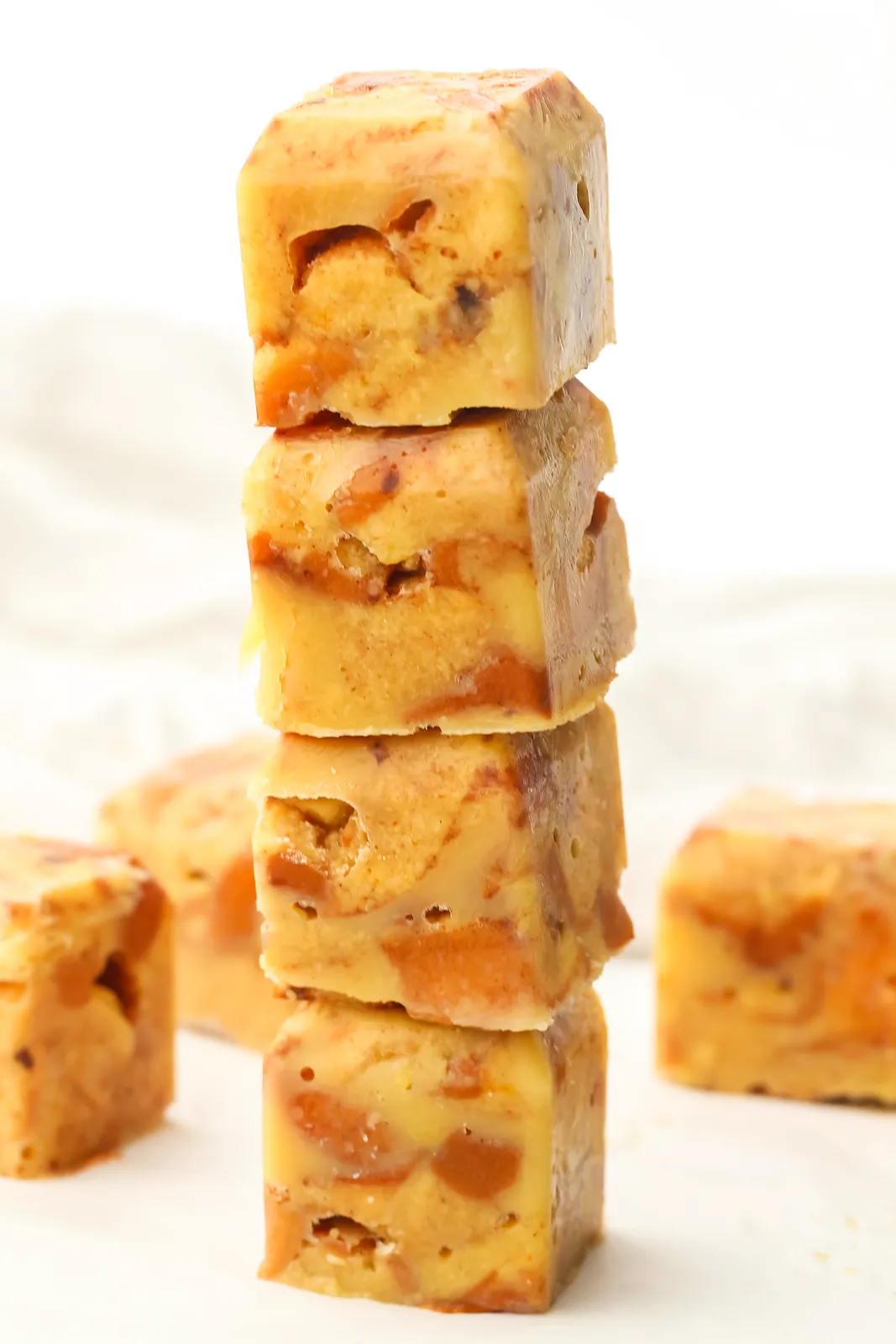 A tall stack of solid custard soaked brioche blocks on a white surface