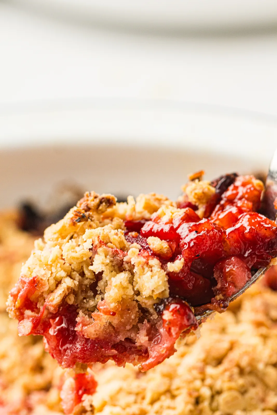 A warm spoonful of syrupy fruit and buttery oats held over the dish